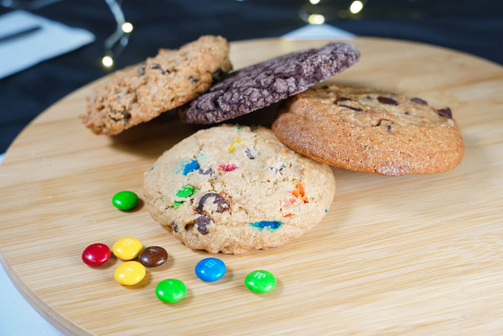 Assorted cookies on wooden board with colorful candies