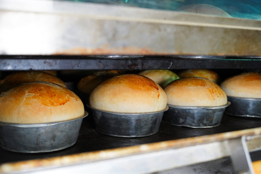Freshly baked bread in metal pans on oven rack