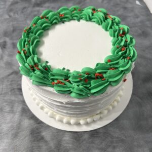 Round cake with green frosting border on table.