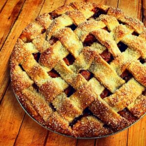 Freshly baked lattice-topped pie on wooden surface