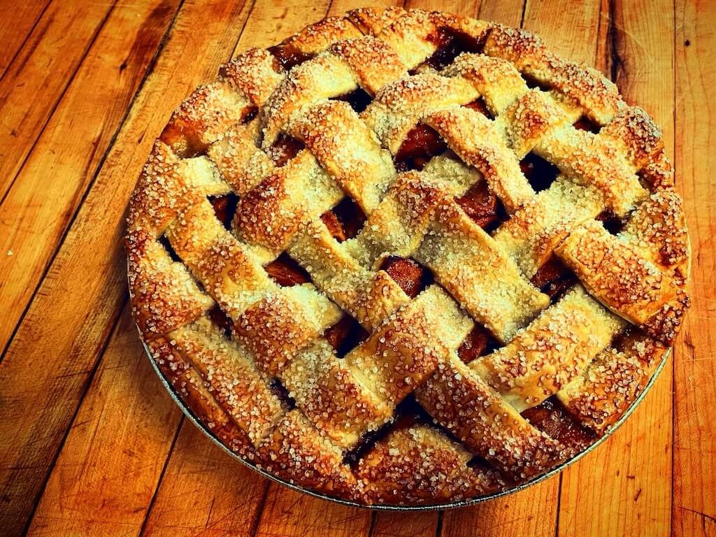 Freshly baked lattice-topped pie on wooden surface