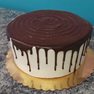 Chocolate drip cake on a golden stand.